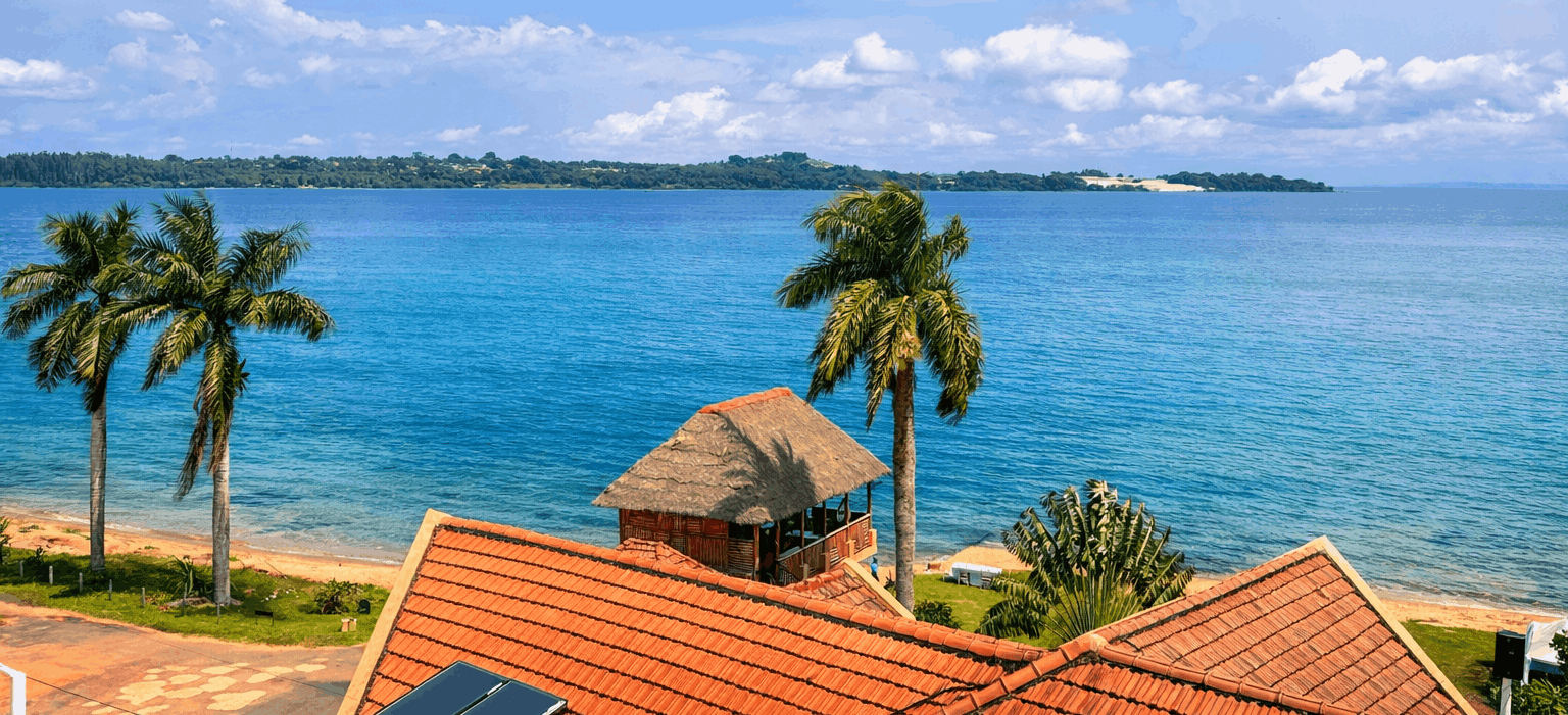 Aerial view of Sienna Beach Hotel's terracotta roofs and thatched gazebo on the shore of Lake Victoria